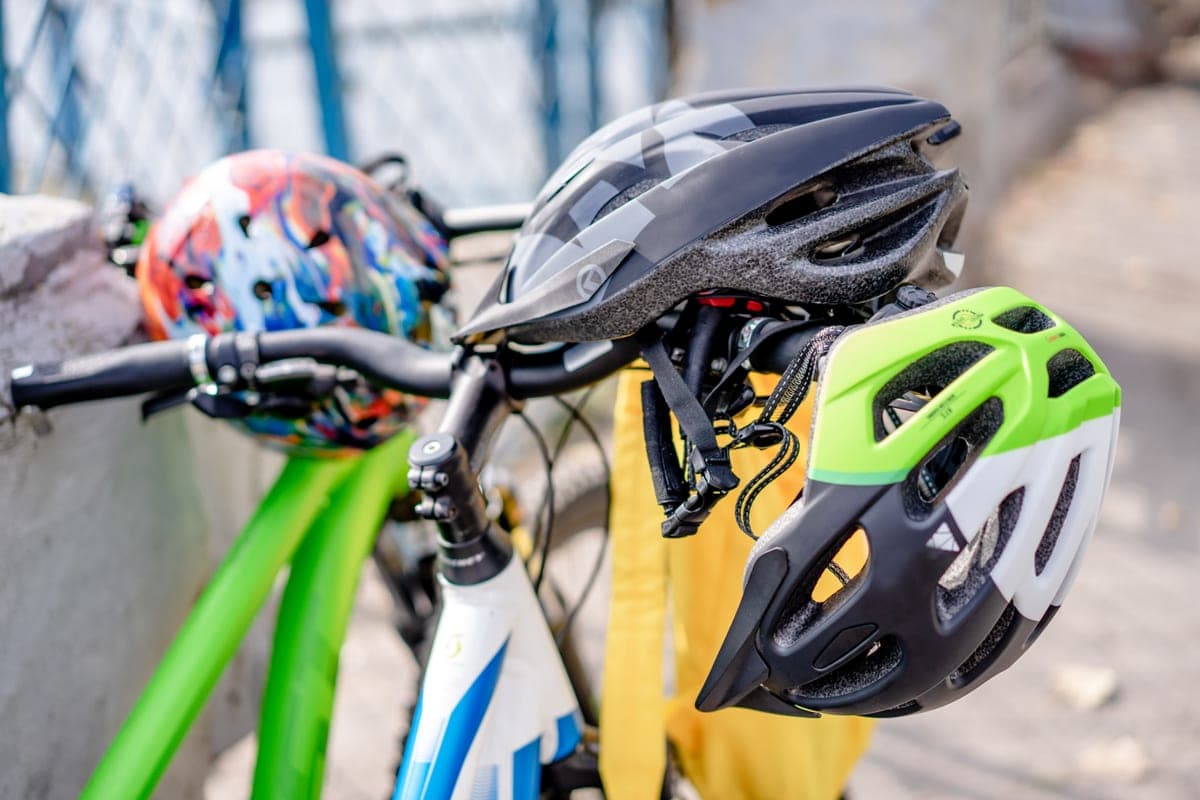 Two bike helmets hanging on bicycle handlebars